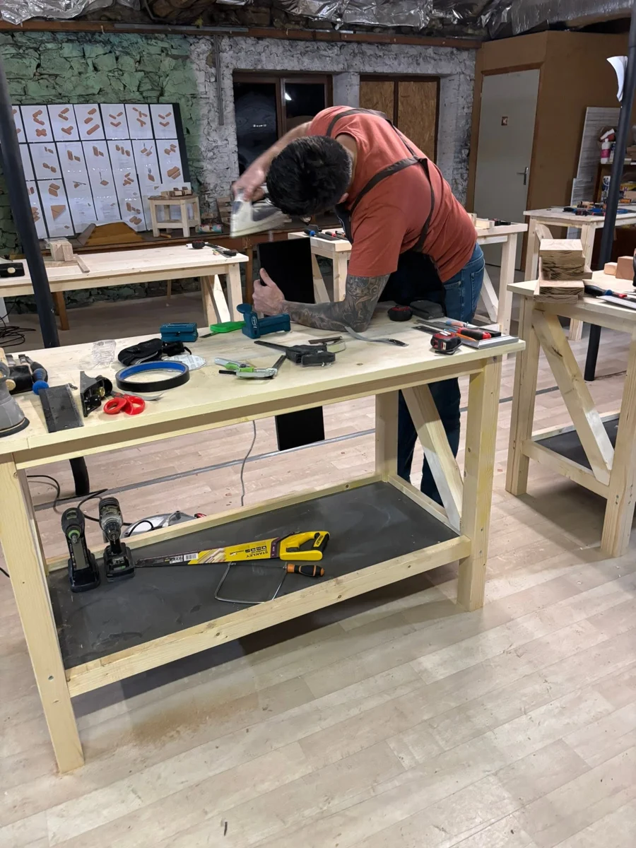 Un participant travaille une étagère sur un établi de l’atelier